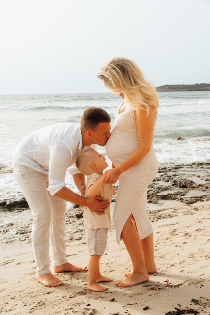 Junge Familie mit einem Kind und Schwangere Frau am Meer
