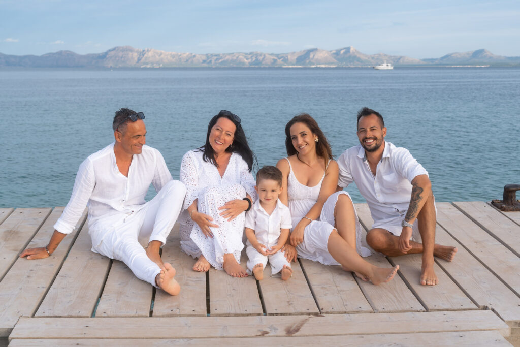 Familie in weißem Outfit sitzt auf dem Holzsteg in Alcudia