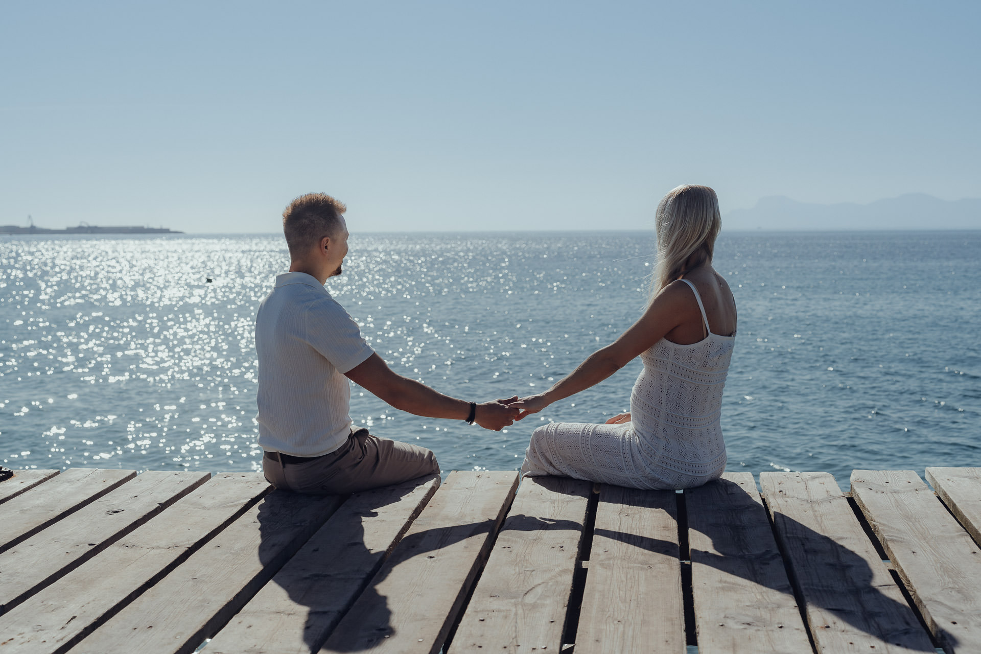 Junges Paar sitzt auf dem Holzsteg in Alcudia