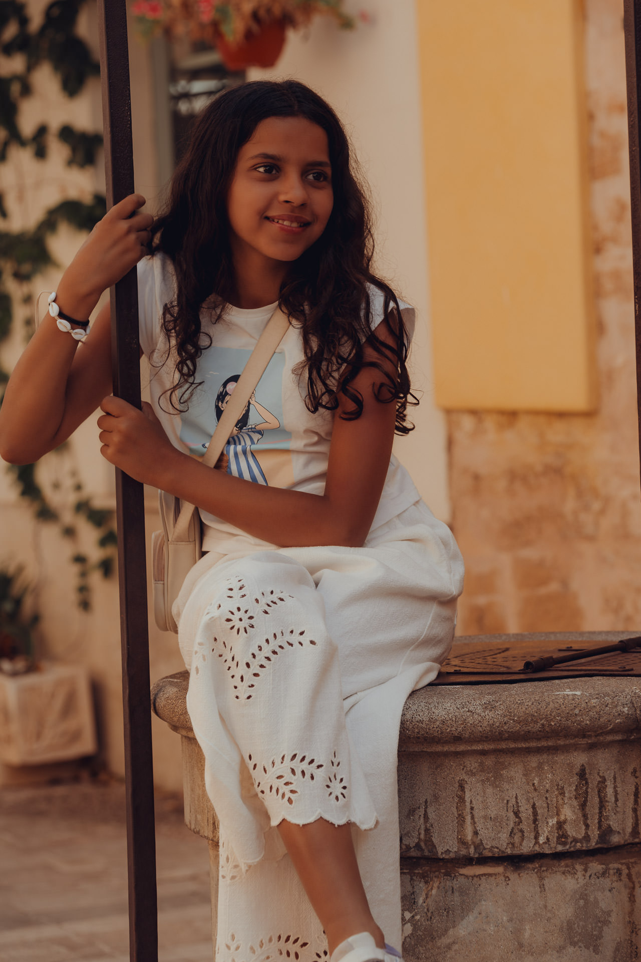 Junges Mädchen sitzt auf einem Brunnen in Alcudia Altstadt