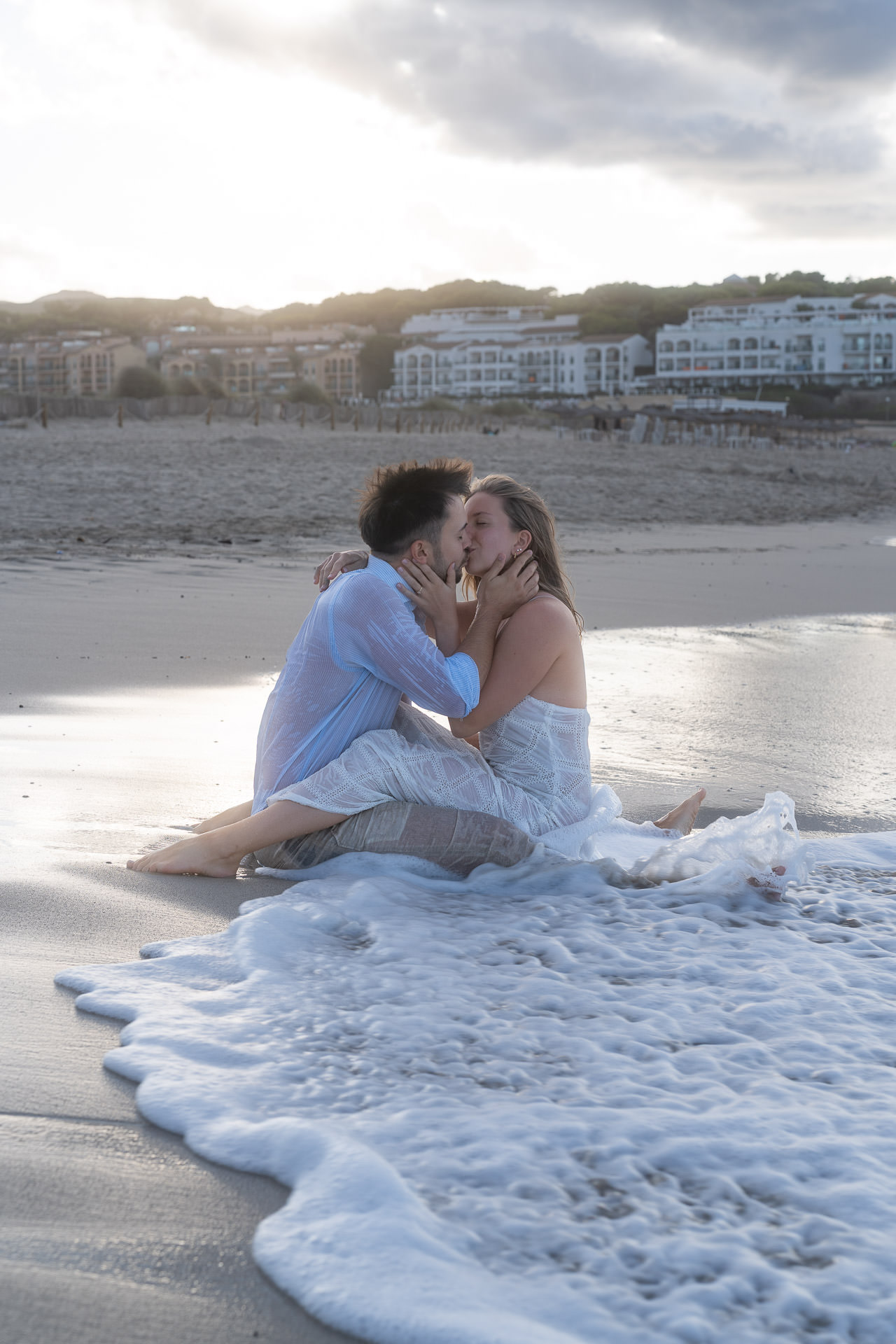 Romantisches Paarshooting Cala Mesquida – verliebtes Paar küsst sich in den Wellen am Strand von Mallorca bei Sonnenuntergang.