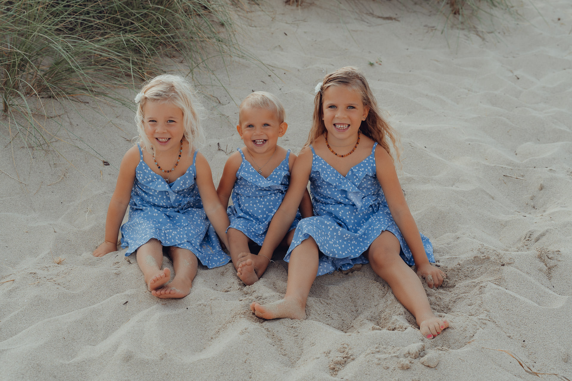 Cala Mesquida Kinderfotoshooting – drei fröhliche Mädchen sitzen lachend im Sand, Sommerfeeling am Strand von Mallorca.