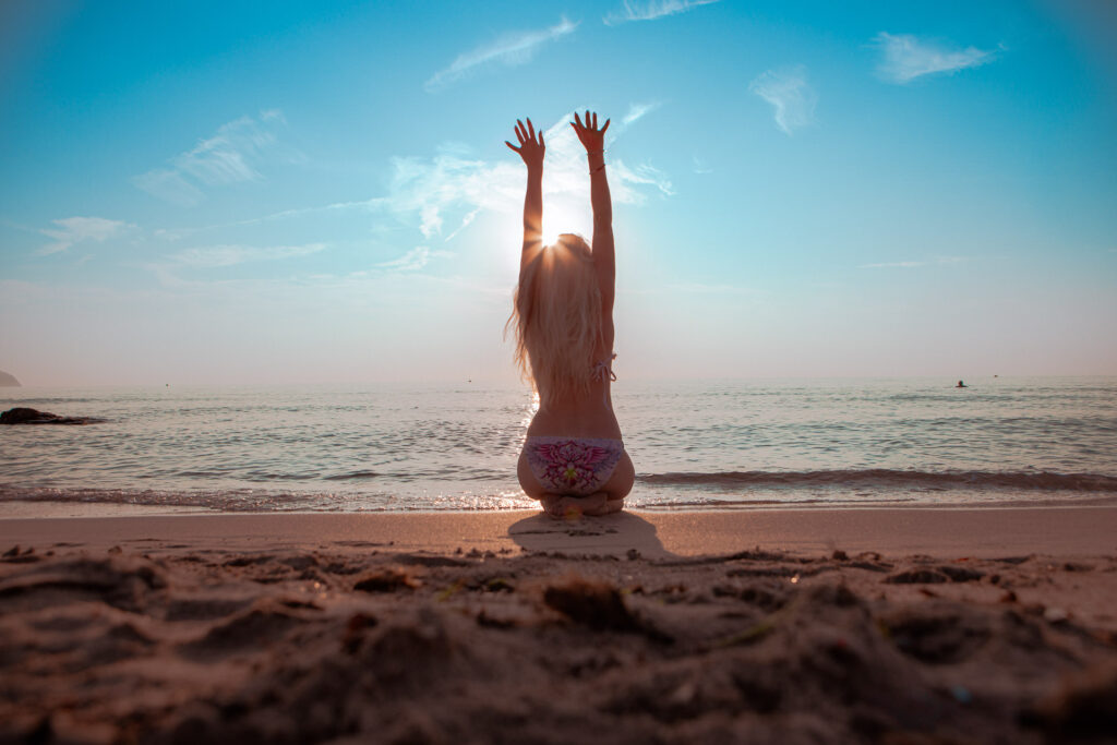 Junges Model sitzt am Strand von Cala Millor und beobachtet den schönen Sonnenaufgang