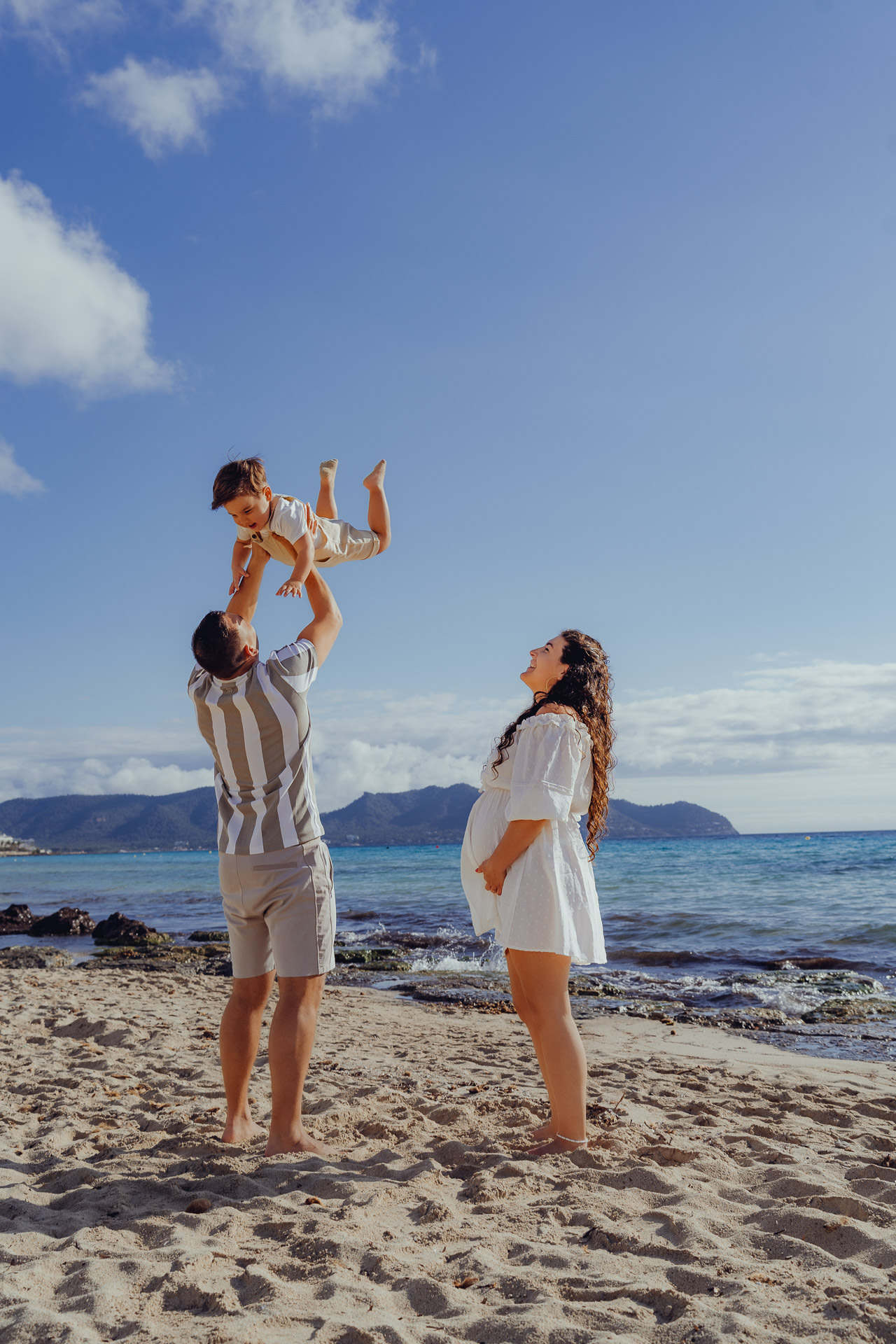 Familien Shooting am Strand von Cala Millor mit einer schwangeren Frau und ihrem Mann der den Sohn hoch in die Luft schmeißt.