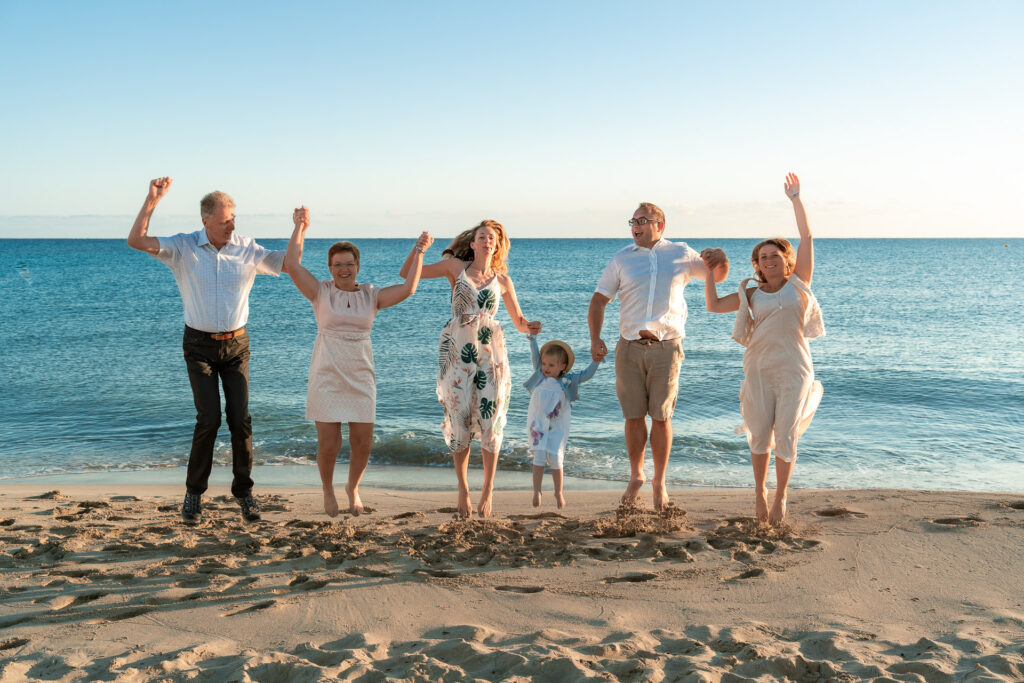 Großfamilie springt für ein Fotoshooting am Meer von Can Picafort