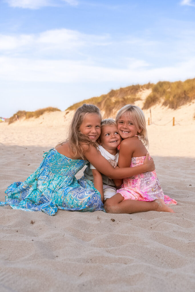 Drei kleine Schwestern sitzen im Sand beim Fotoshooting