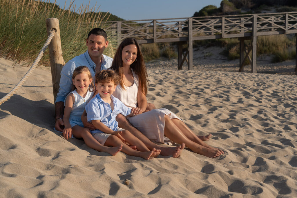 Junge Familie mit 2 Kindern sitzt im Sand am Strand