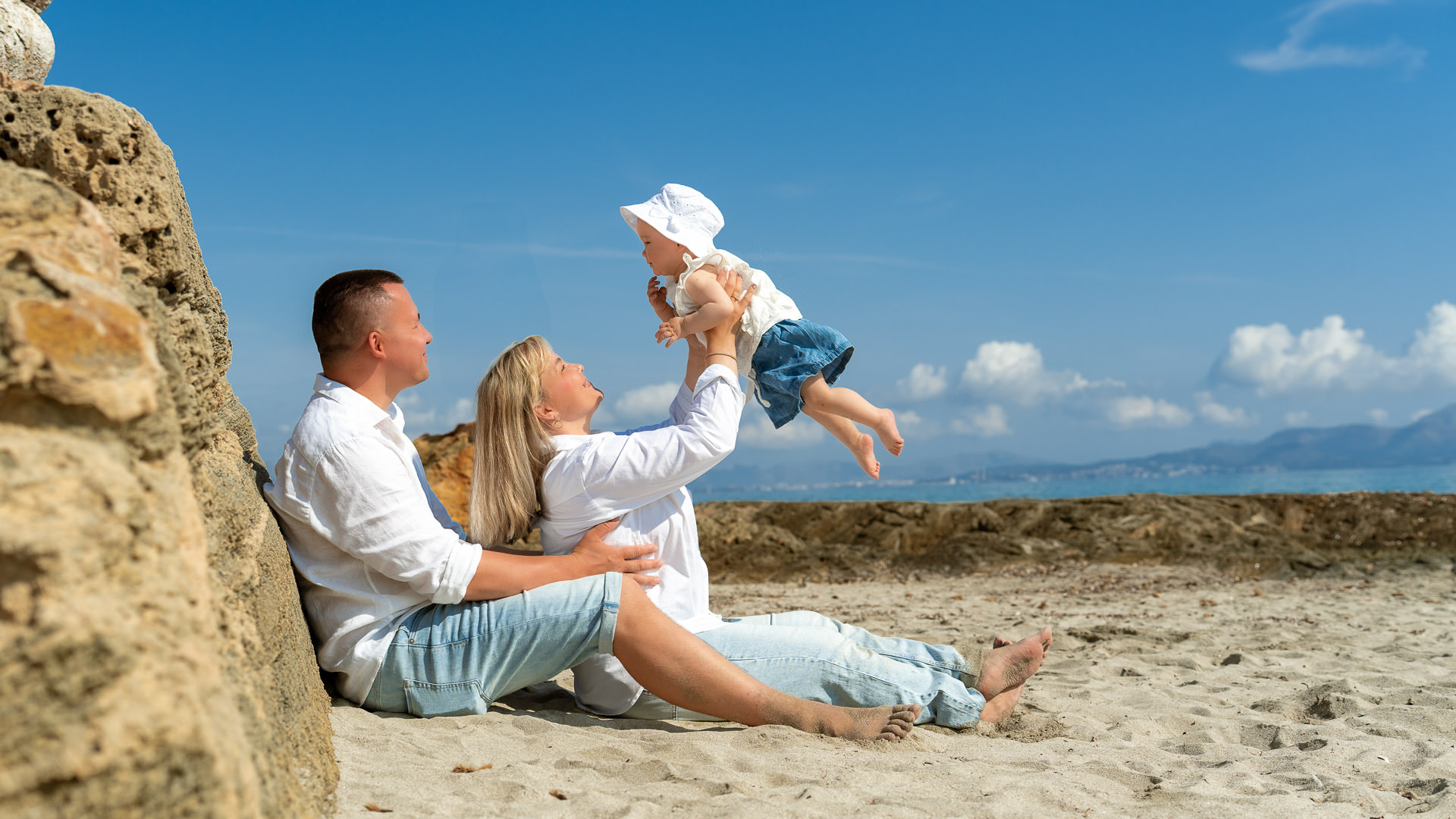 Can Picafort Fotoshooting Eltern halten freudig ihr Baby hoch zum Fotoshooting
