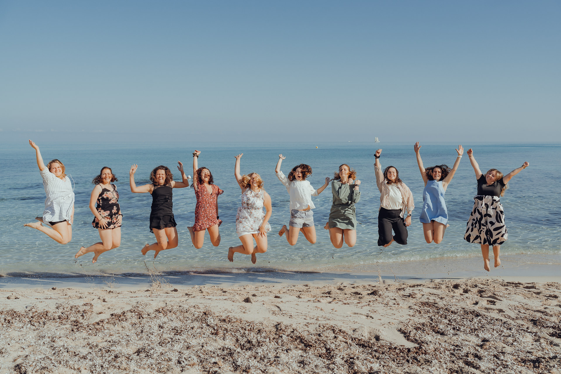10 Frauen springen für ein Fotoshooting gemeinsam in die Luft.