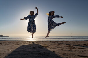 Mallorca Bestfriends Shooting 2 Frauen springen akrobatisch für ein Fotoshooting am Strand von Mallorca in die Luft