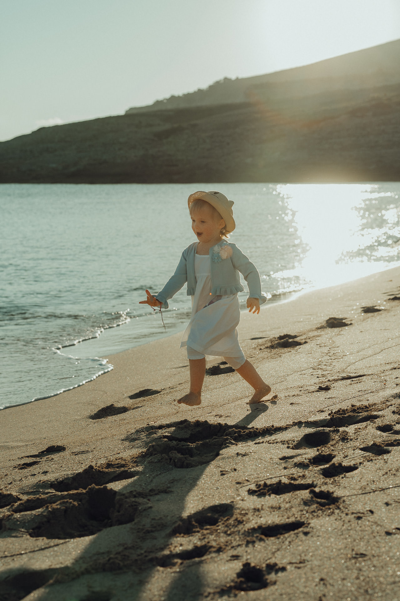 Kleines Mädchen läuft barfuß am Strand von Mallorca im Abendlicht