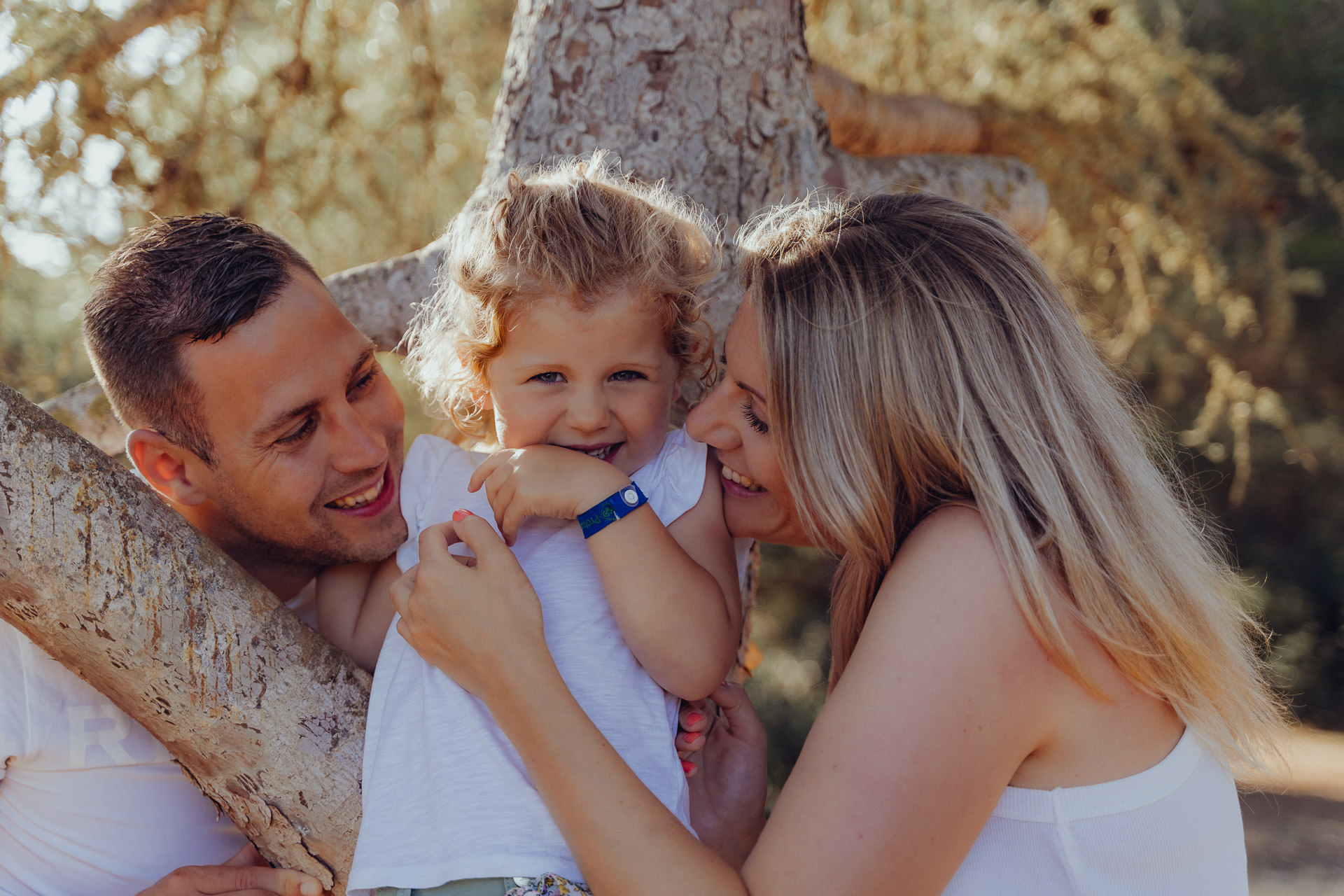 Familie kuschelt und lacht gemeinsam im Baum beim Mallorca Familien Shooting