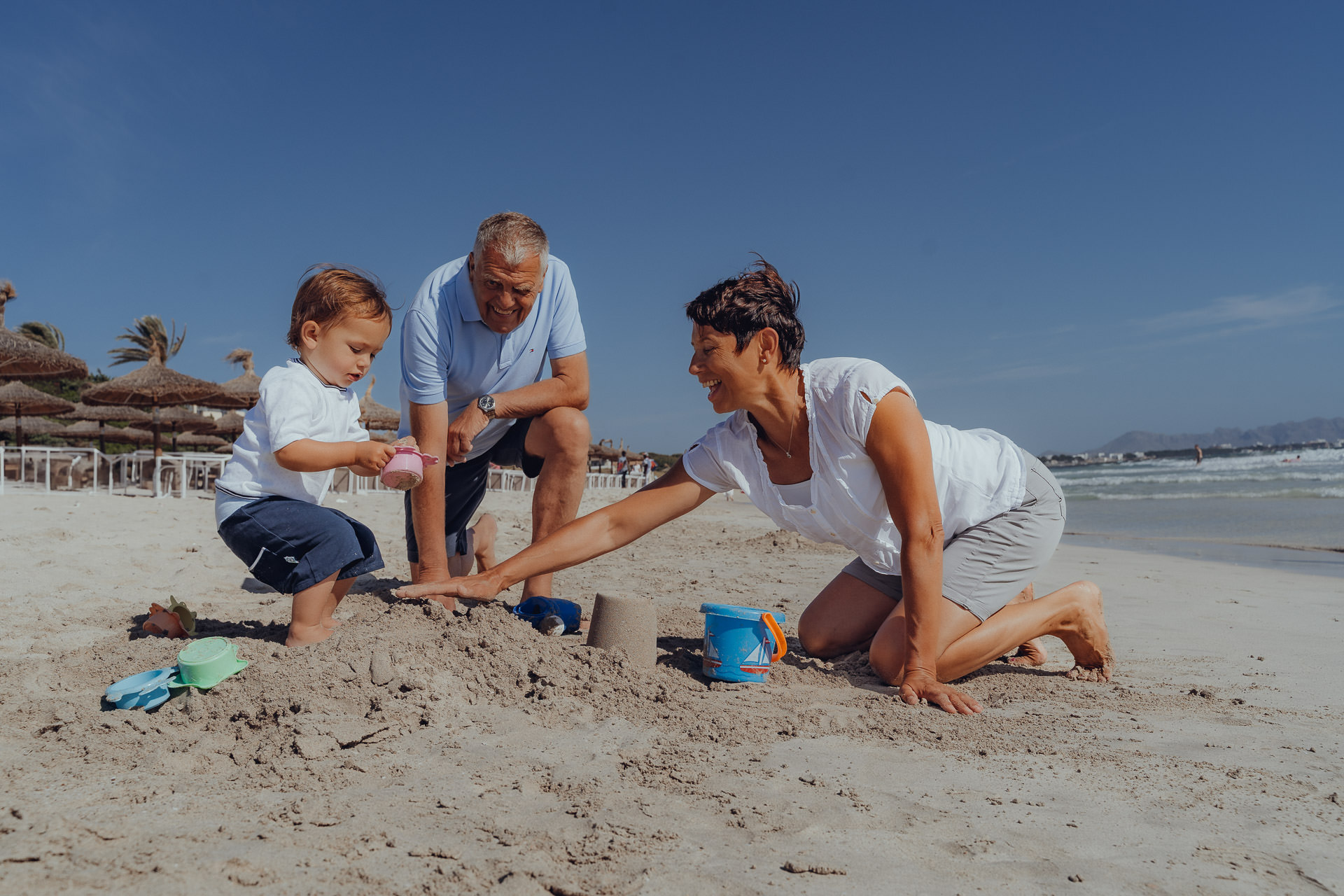 Großeltern spielen mit Enkelkind im Sand beim Mallorca Familien Shooting