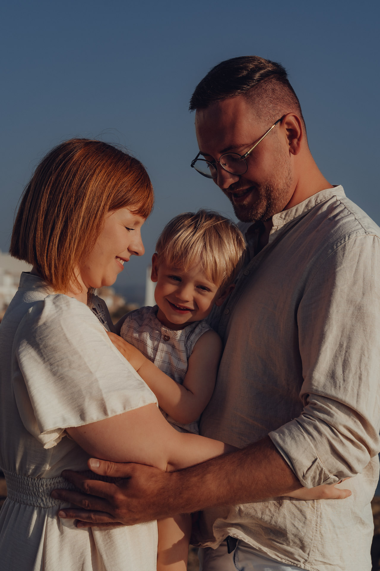 Eltern umarmen ihr Kind bei Sonnenuntergang am Strand beim Mallorca Familien Shooting