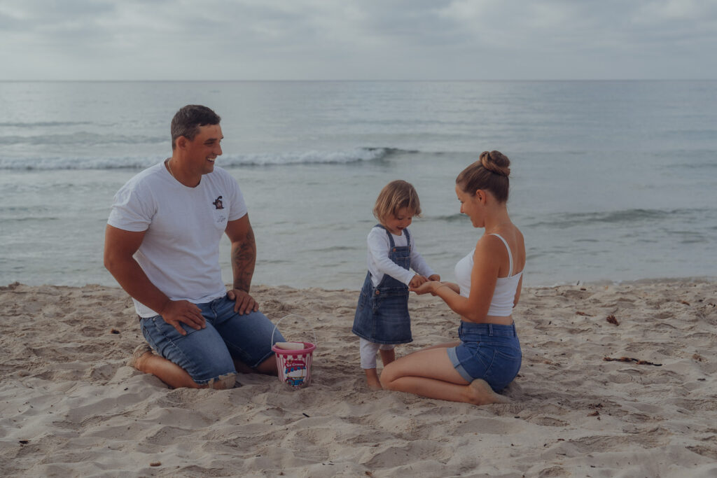 Junge Familie spielt mit Tochter im Sand in Sa Coma