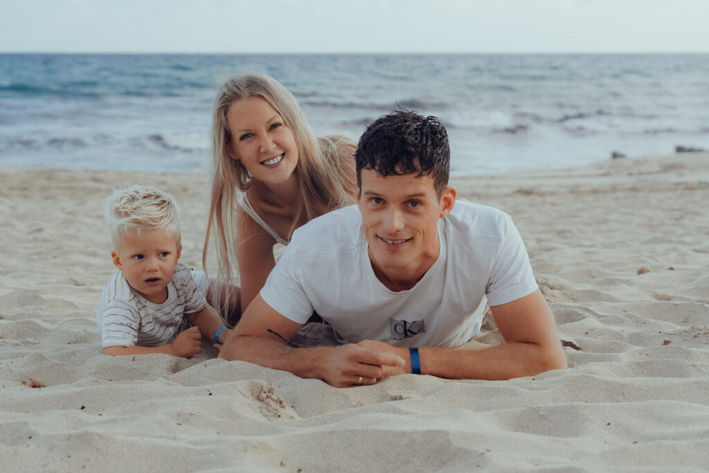 Junge Familie liegt beim Fotoshooting am Strand von Cala Millor