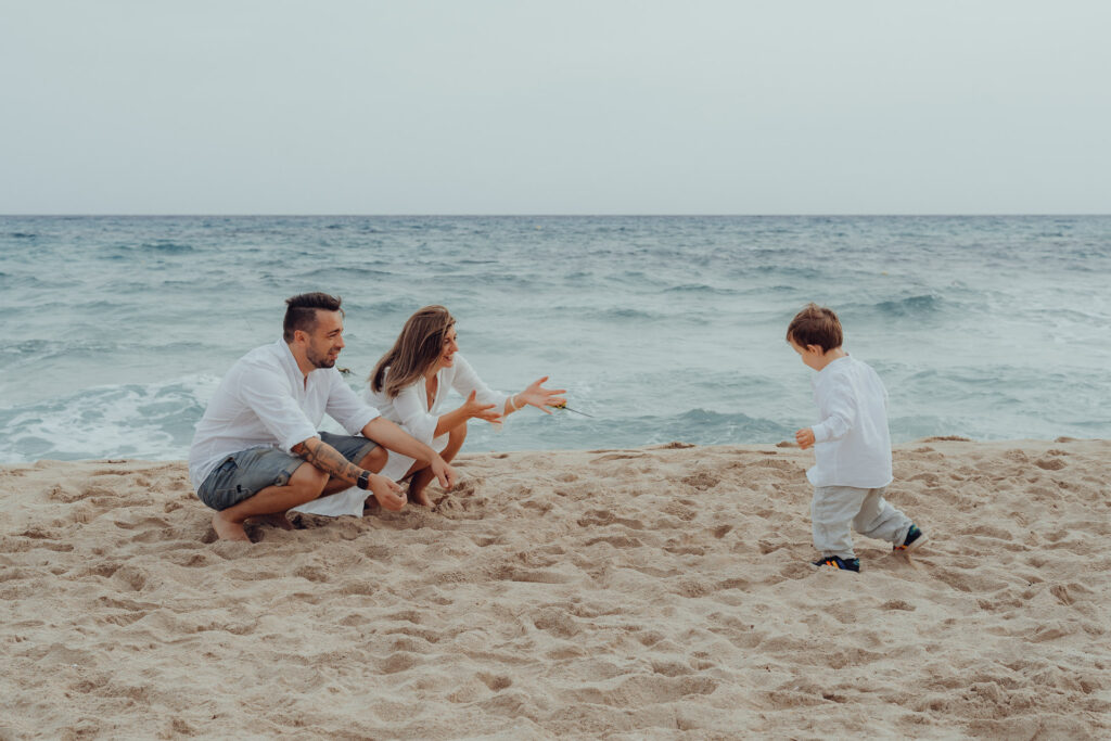 Kind rennt am Strand in die offenen Arme der Eltern