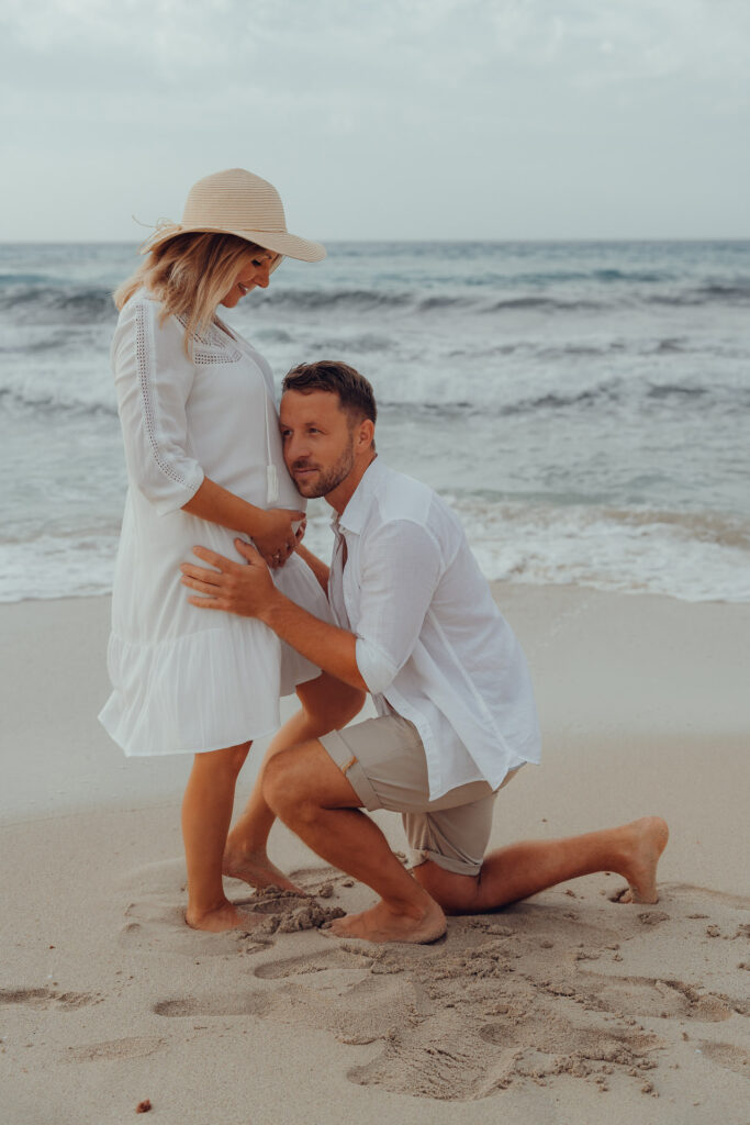 Intimes Babybauch-Fotoshooting am Strand von Mallorca – werdende Eltern in liebevoller Pose vor der Meereskulisse. Mallorca Fotograf für besondere Momente.