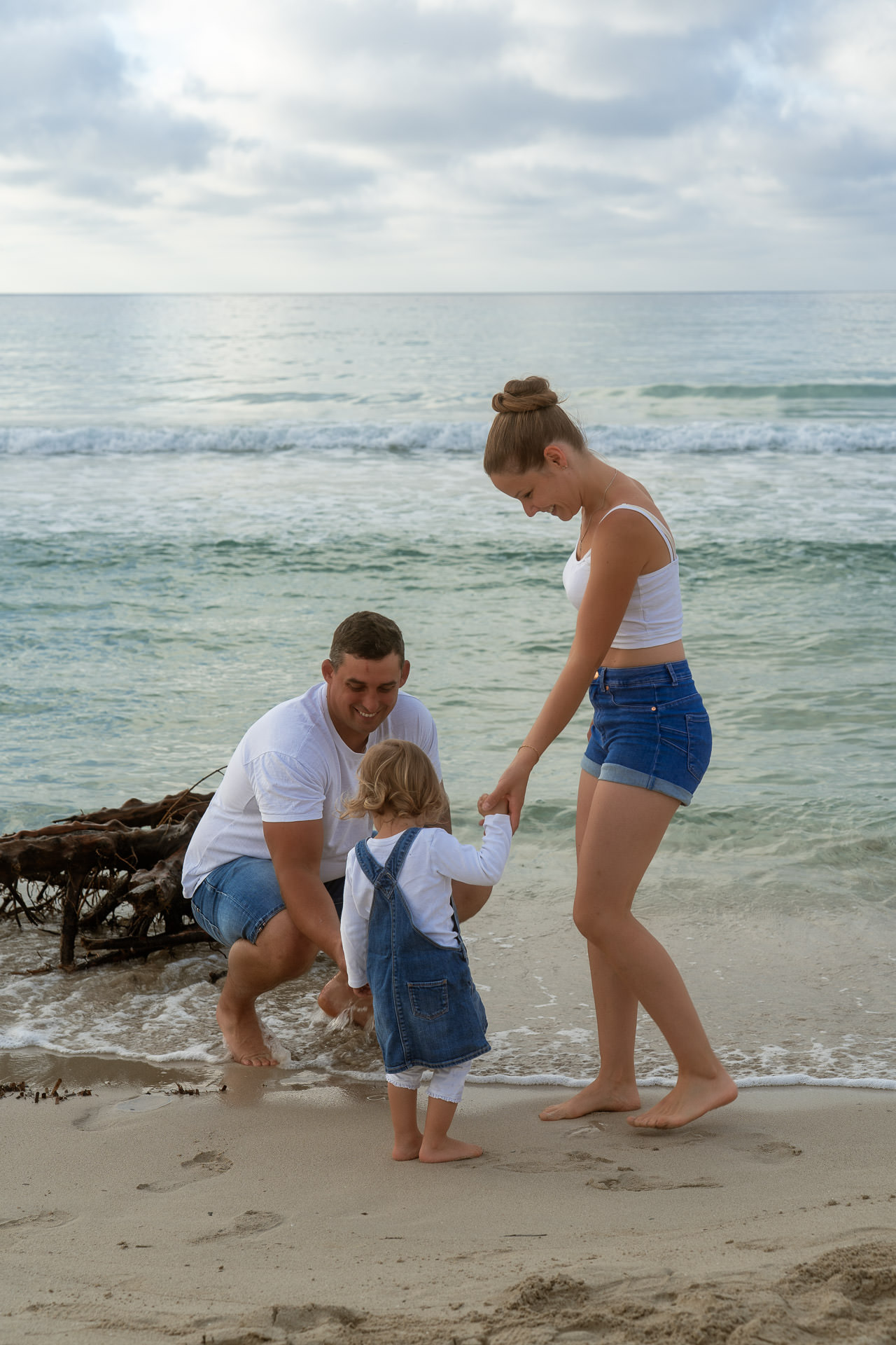 Mallorca Urlaubs Shooting Junge Familie spielt mit Kleinkind am Strand von Cala Millor bei bewölktem Himmel