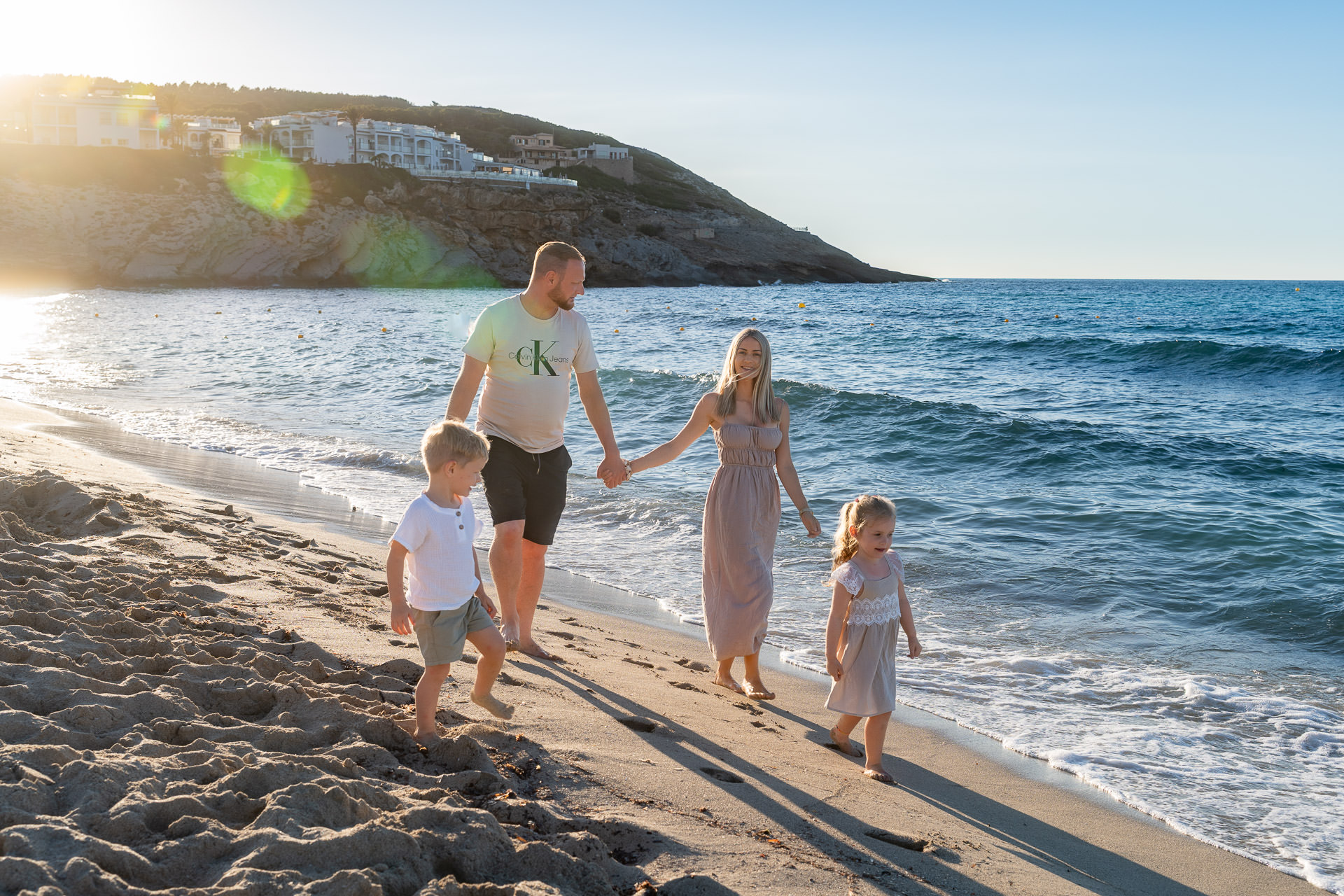 Mallorca Urlaubs Shooting Familie mit zwei Kindern spaziert barfuß bei Sonnenuntergang am Strand entlang
