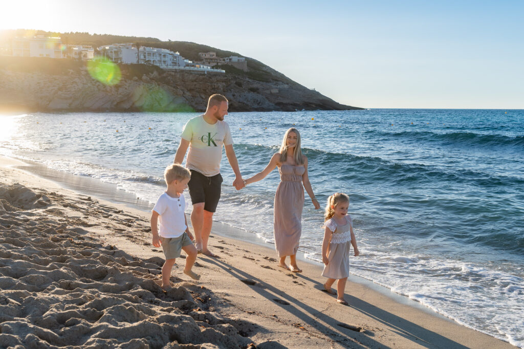 Familie mit 2 Kindern beim Sonnenuntergang Spaziergang am Meer von Mallorca