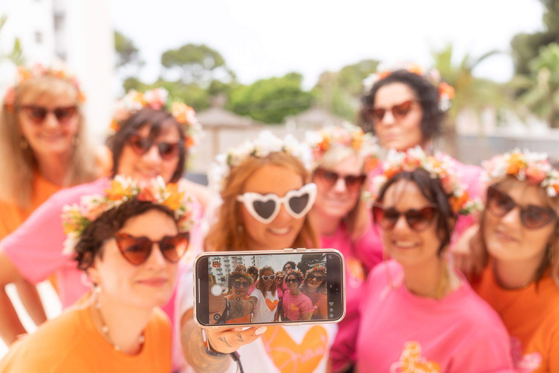 Fröhliche JGA-Gruppe mit Blumenkränzen posiert für ein Selfie, Braut im Mittelpunkt – Junggesellinnenabschied auf Mallorca.
