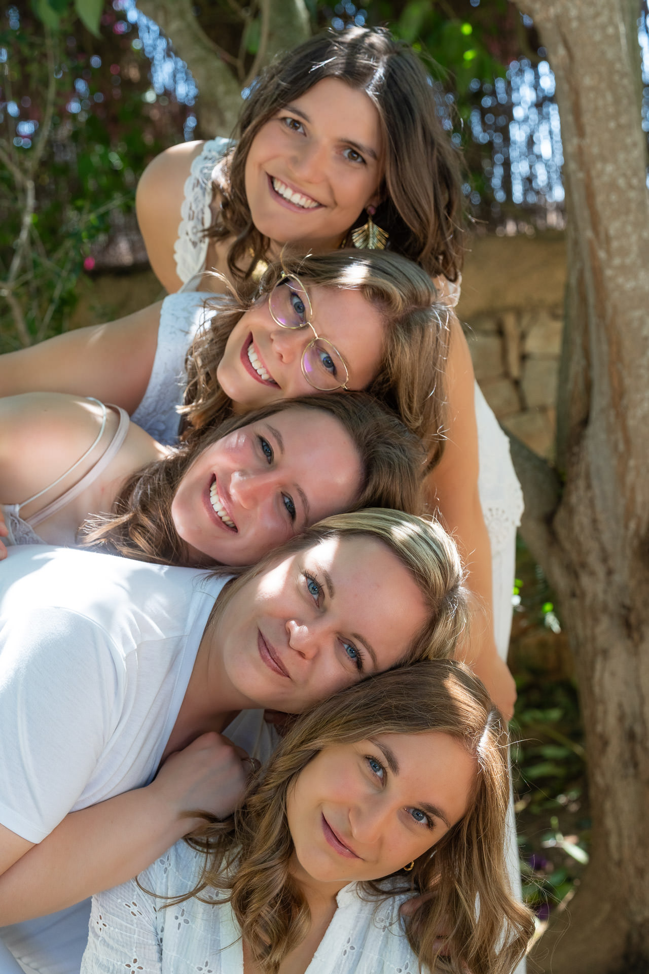 JGA Mallorca: Fünf Freundinnen stapeln sich lachend beim Shooting im Garten, alle in Weiß gekleidet.