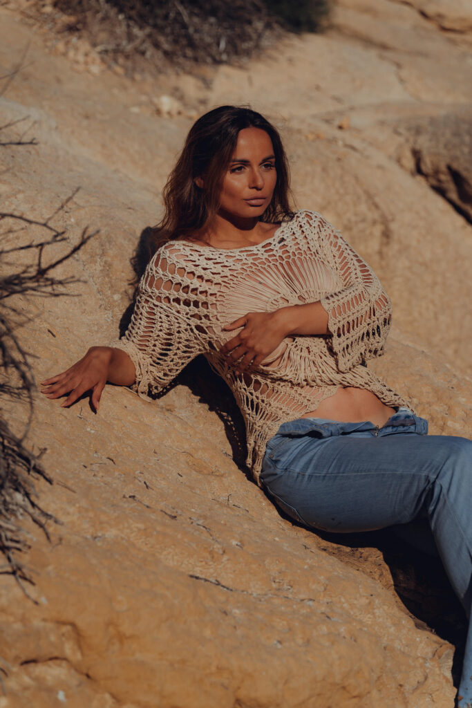 Dunkel Blondes Model sitzt in nasser Jeans und mit einem Netzoberteil auf einem Felsen in Mallorca