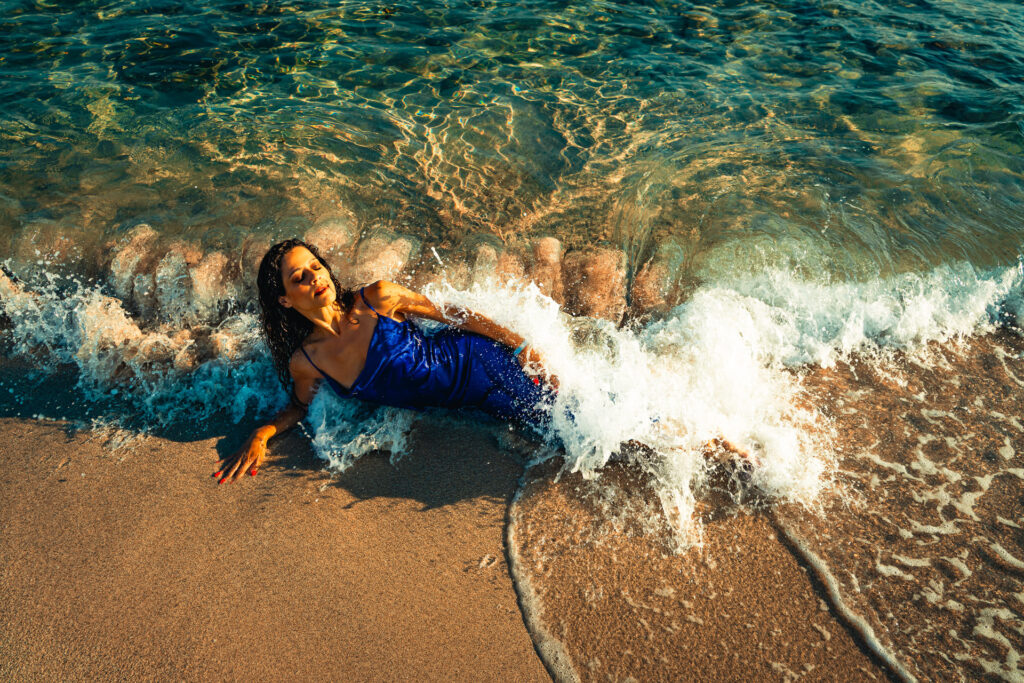 Model im blauen Kleid genießt die Wellen am Strand beim Mallorca Model Shooting