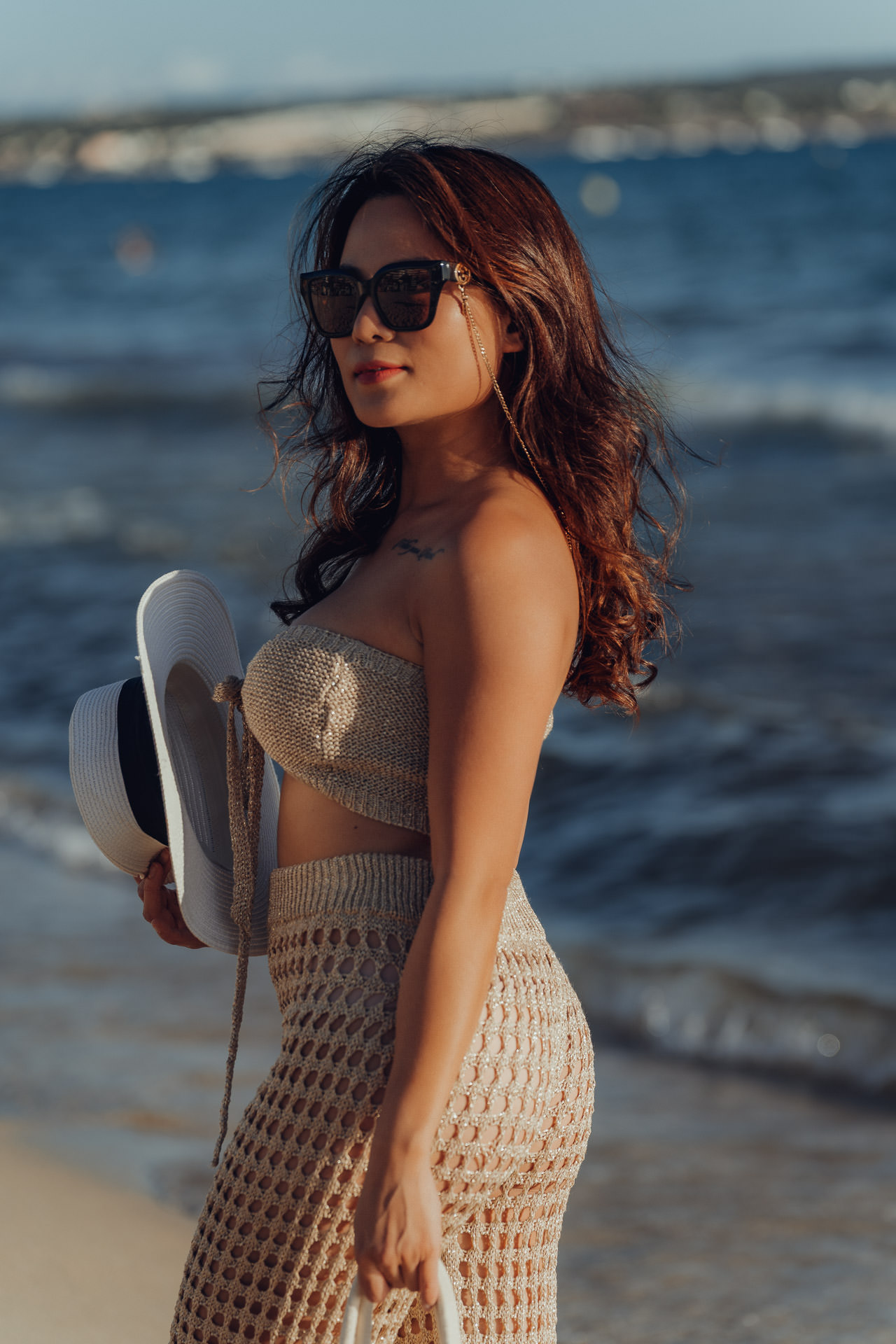 Frau mit Sonnenbrille und Strohhut am Strand, sommerliche Boho-Atmosphäre auf Mallorca