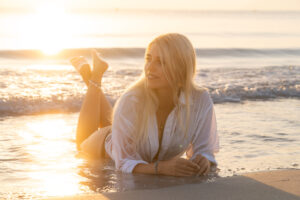 Model liegt im seichten Wasser der Playa de Muro und im Hintergrund geht die Sonnen auf