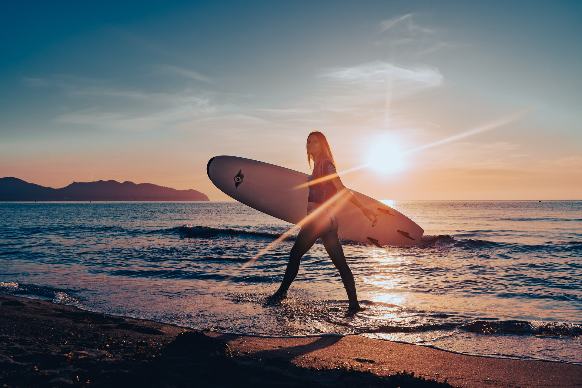 Mallorca Sonnenaufgang Shooting Model mit Surfbrett läuft bei Sonnenaufgang am Strand in Cala Millor