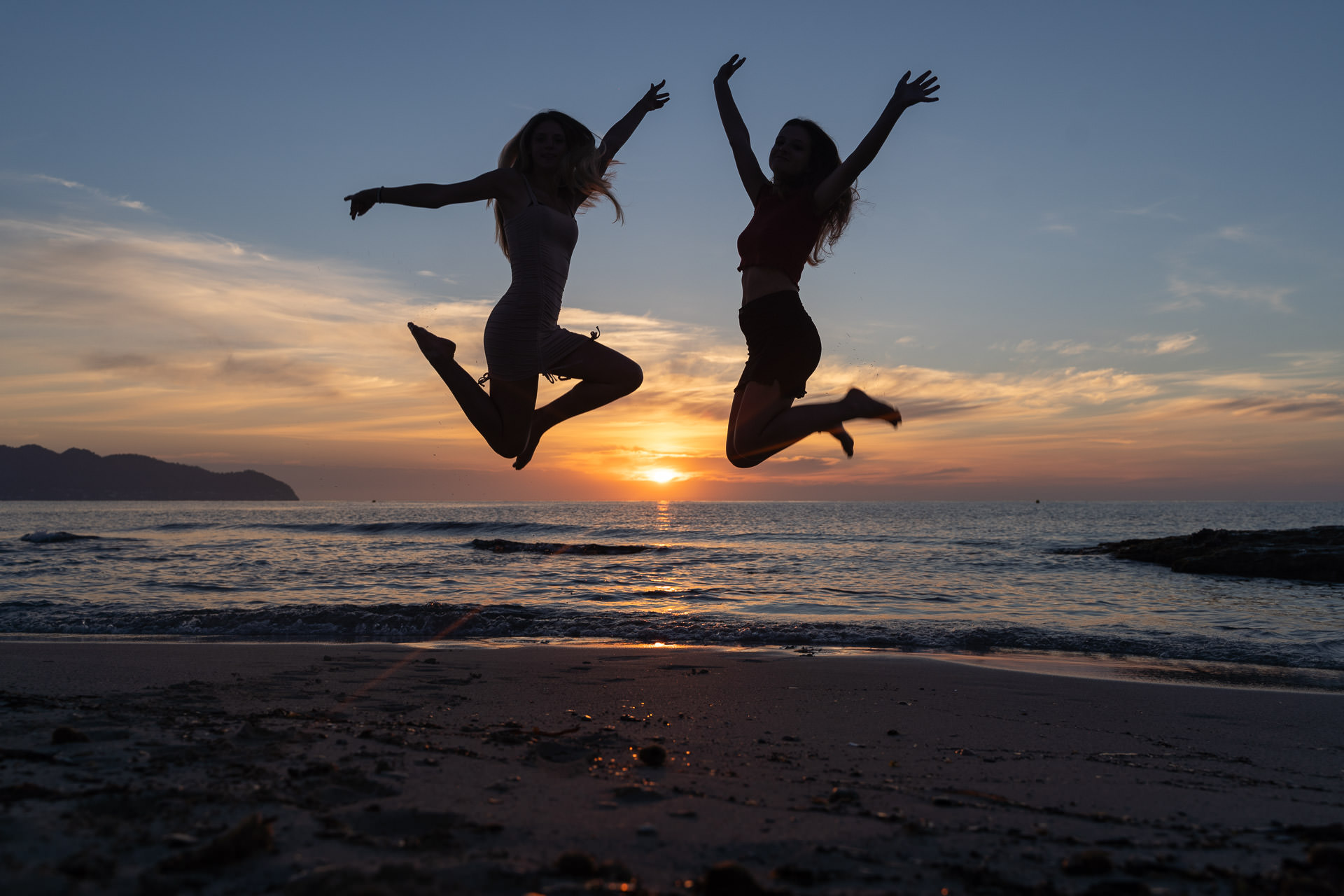 Mallorca Sonnenaufgang Shooting 2 Freundinnen springen für eine Fotoshooting bei Sonnenaufgang an der Cala Agulla hoch in die Luft.