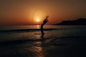 Sonnenaufgang in Cala Rajada und ein Model steht im Meer