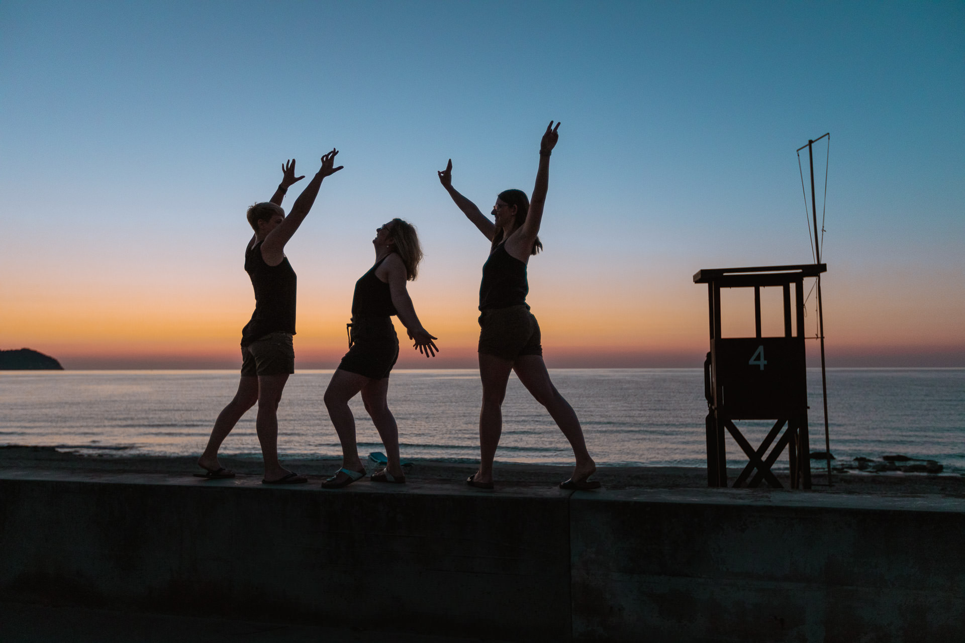 Mallorca Sonnenaufgang Shooting 3 Mädchen tanzen auf der Mauer zum Strand von Cala Millor, iim Hintergrund kommt die Sonne aus dem Meer