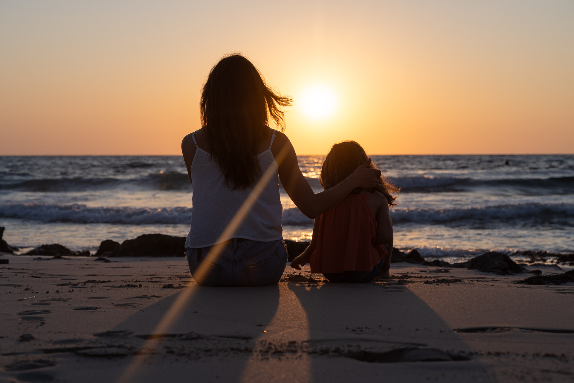 Mallorca Sonnenuntergang Shooting Mutter sitzt mir Kind im Sand am Strand von Mallorca und schaut zum Sonnenuntergang