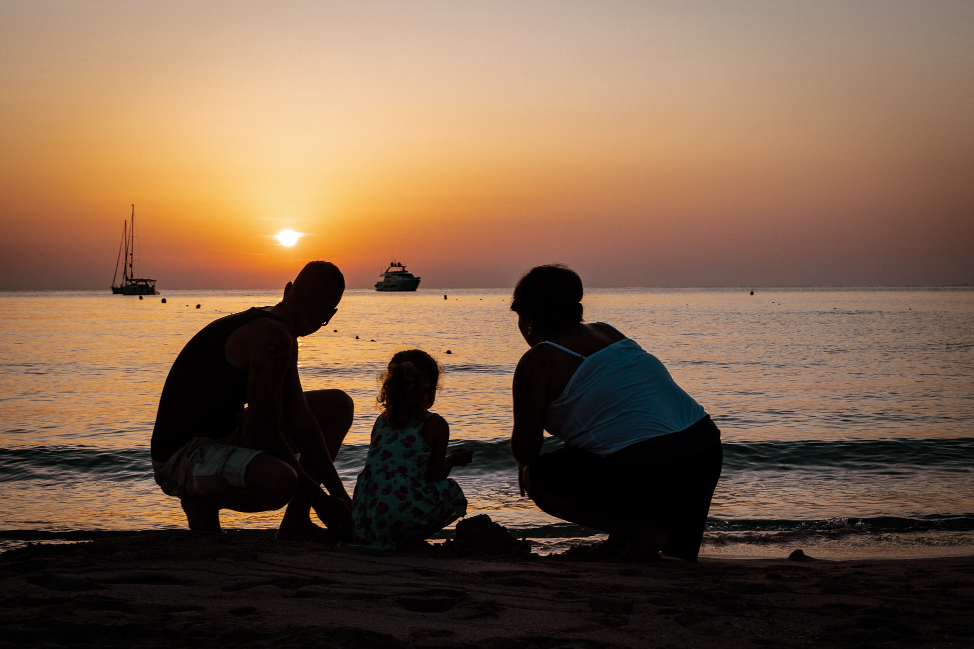 Mallorca Sonnenuntergang Shooting Kleine Familie mit Kleinkind sitzt am Meer und schaut zum Untergang