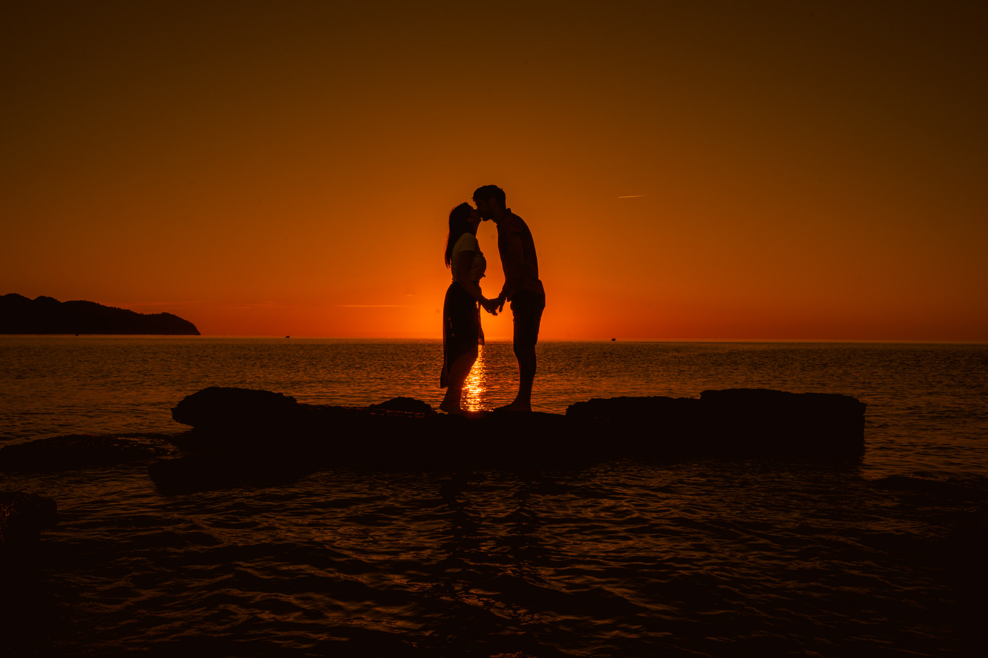 Mallorca Sonnenuntergang Shooting Paar küsst sich Händchen haltend im Sonnenuntergang