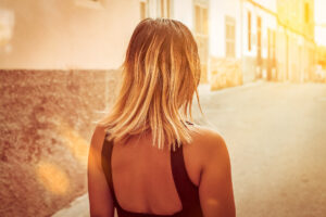 Model mit schulterlangen glatten Haaren läuft Richtung Sonnenuntergang iin den Gassen von Palma