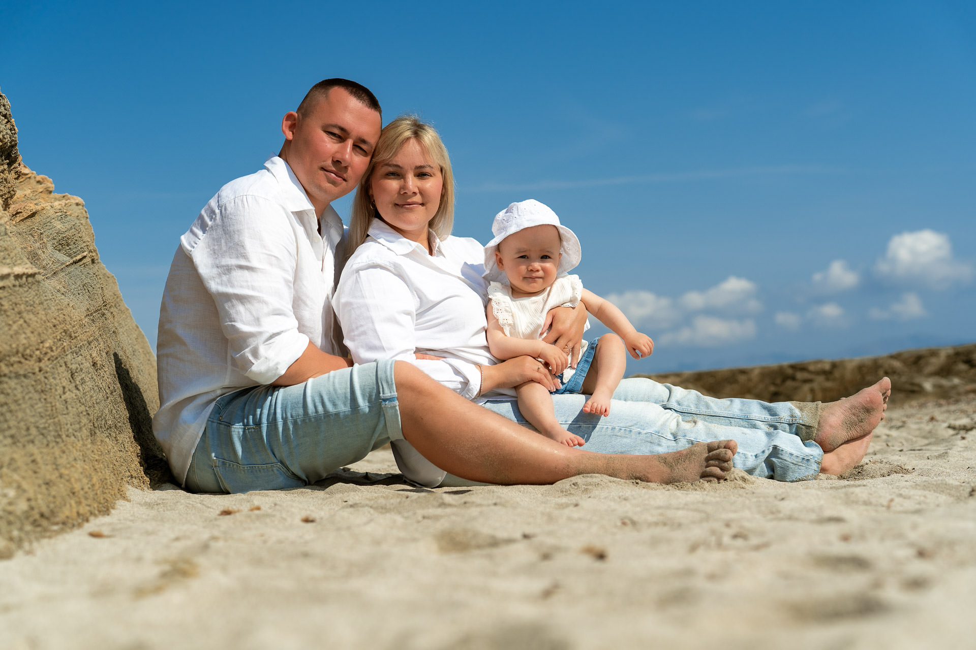 Mallorca Urlaubs Shooting Junge Familie sitzt mit kleinem Baby im Sand am Strand von Can Picafort
