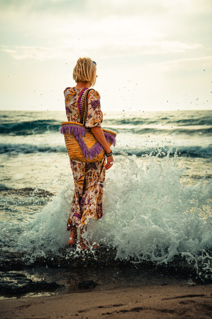 Elegante Frau steht im Meer während das Wasser der wellen hoch spritzt