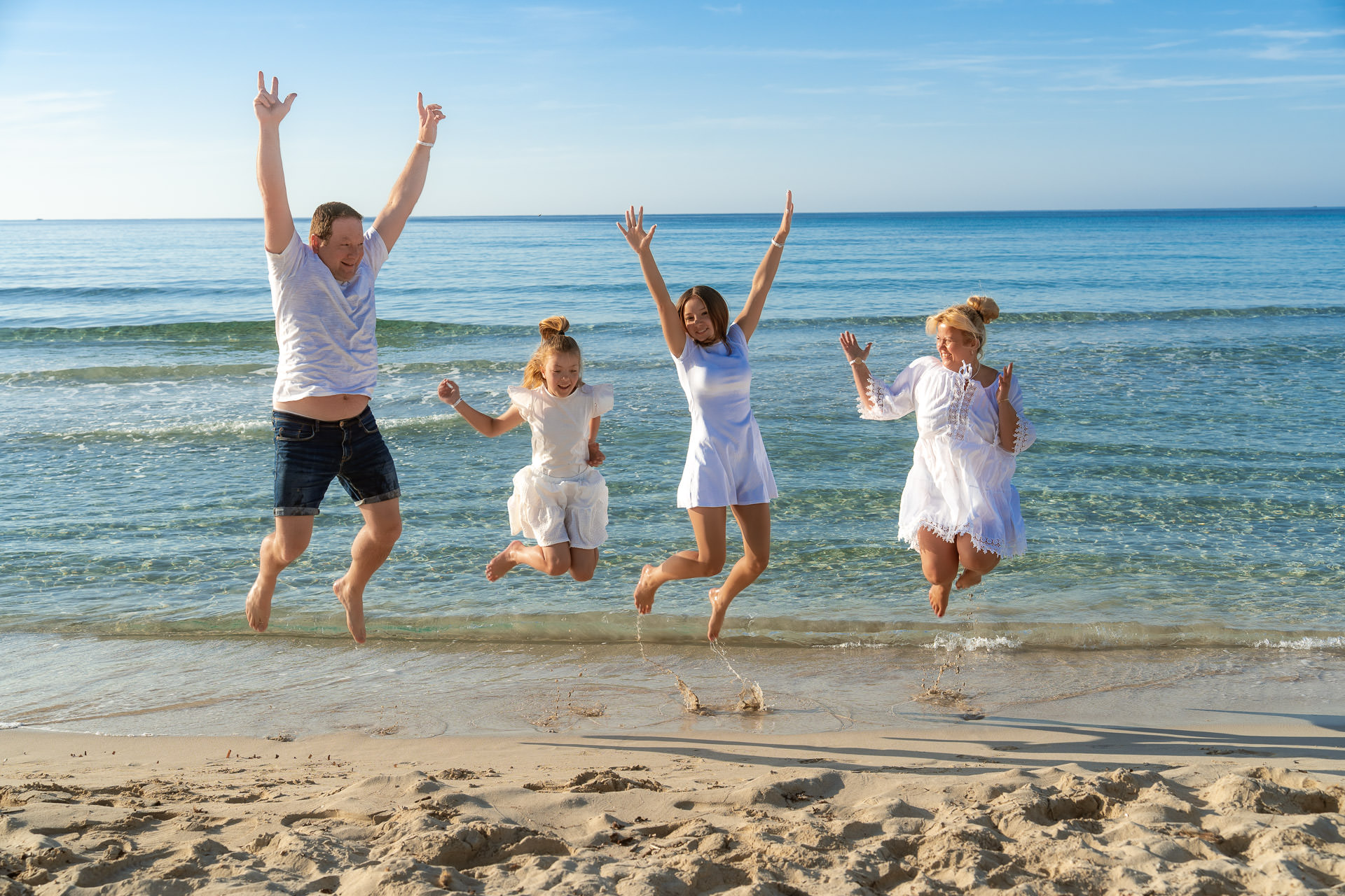 Playa de Muro Fotoshooting Familie springt gemeinsam beim Fotoshooting an der Playa de Muro in die Luft.