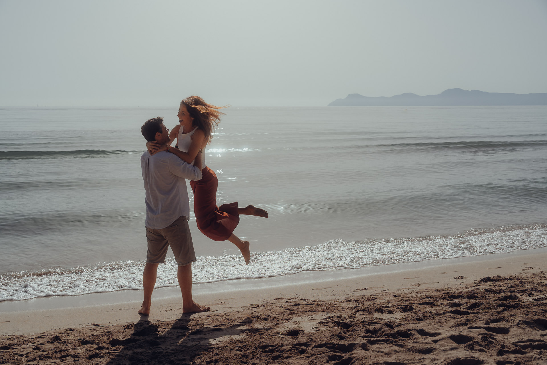 Playa de Muro Fotoshooting Sie springt verliebt in die Arme ihres Freundes am Strand der Playa de Muro
