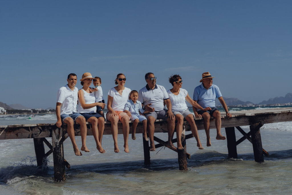 Familie sitzt auf dem Holzsteg an der Playa de Muro