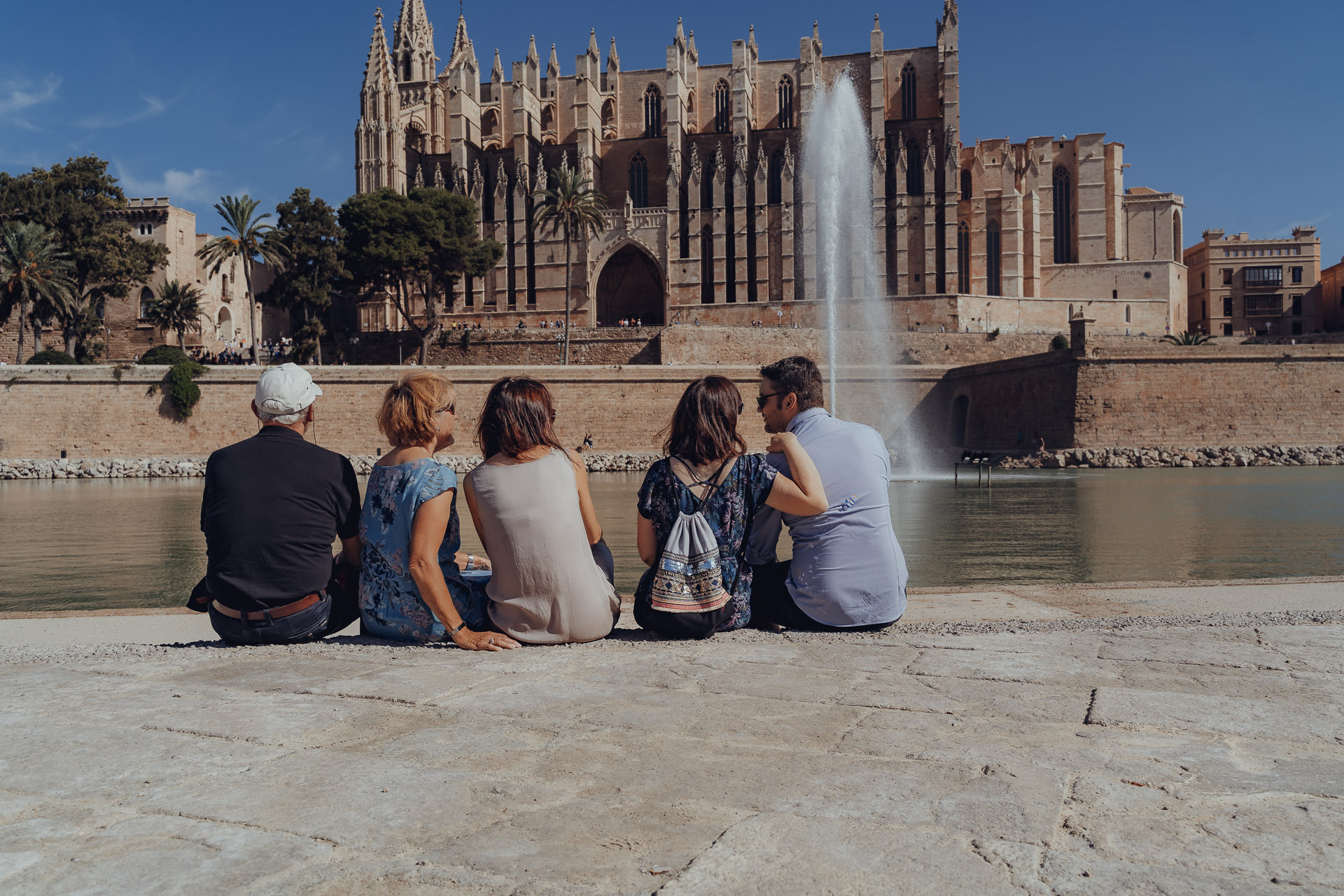 Familie sitzt am See vor der Kathedrale von Palma und genießt die Sonne auf Mallorca.