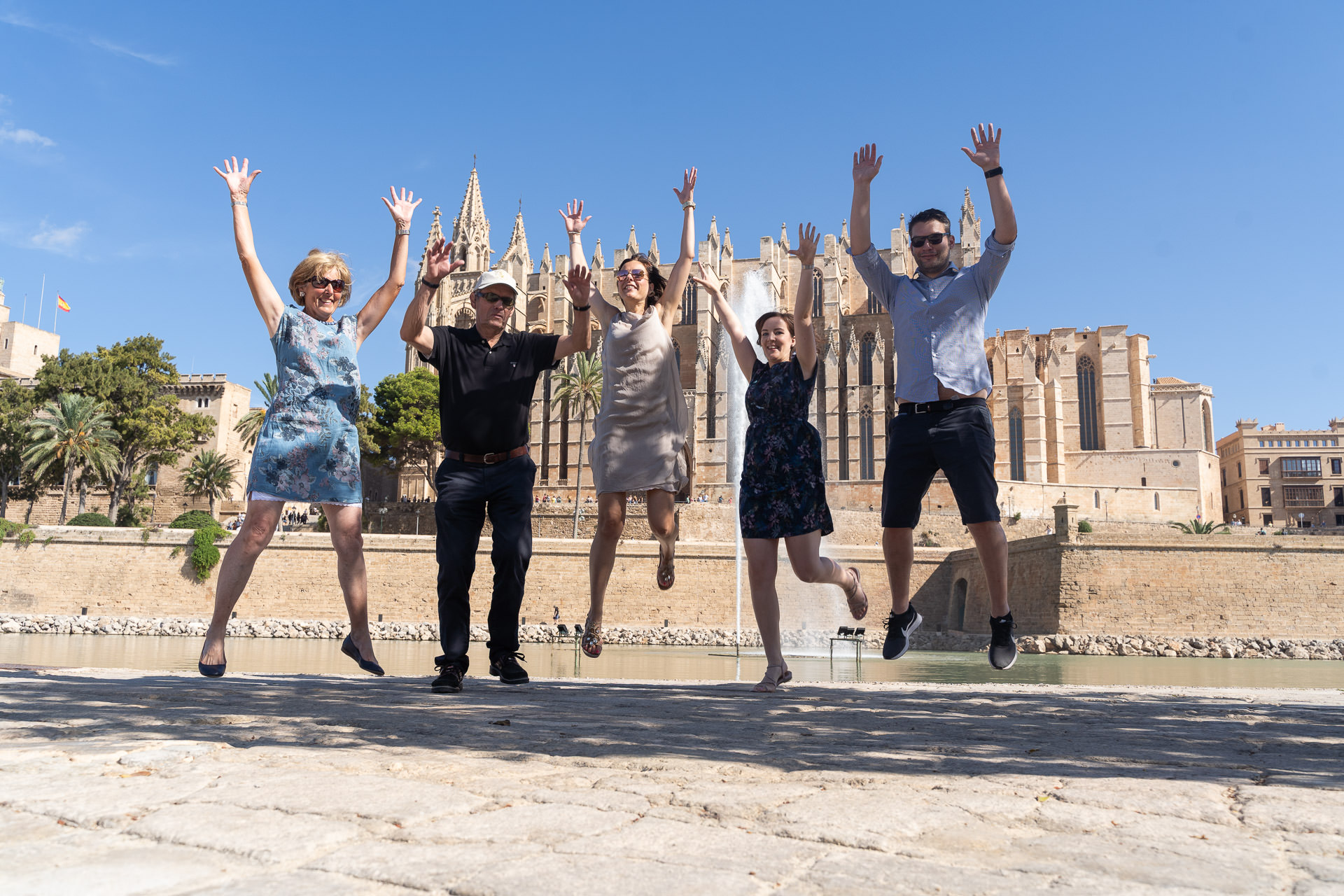 Fünf Menschen springen vor der Kulisse der Kathedrale in Palma in die Luft.