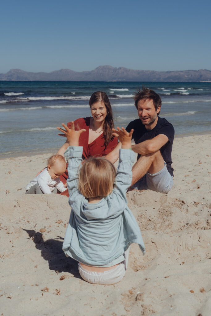 Familie spielt und lacht gemeinsam im Sand an der Playa de Muro – authentische Urlaubsfotos