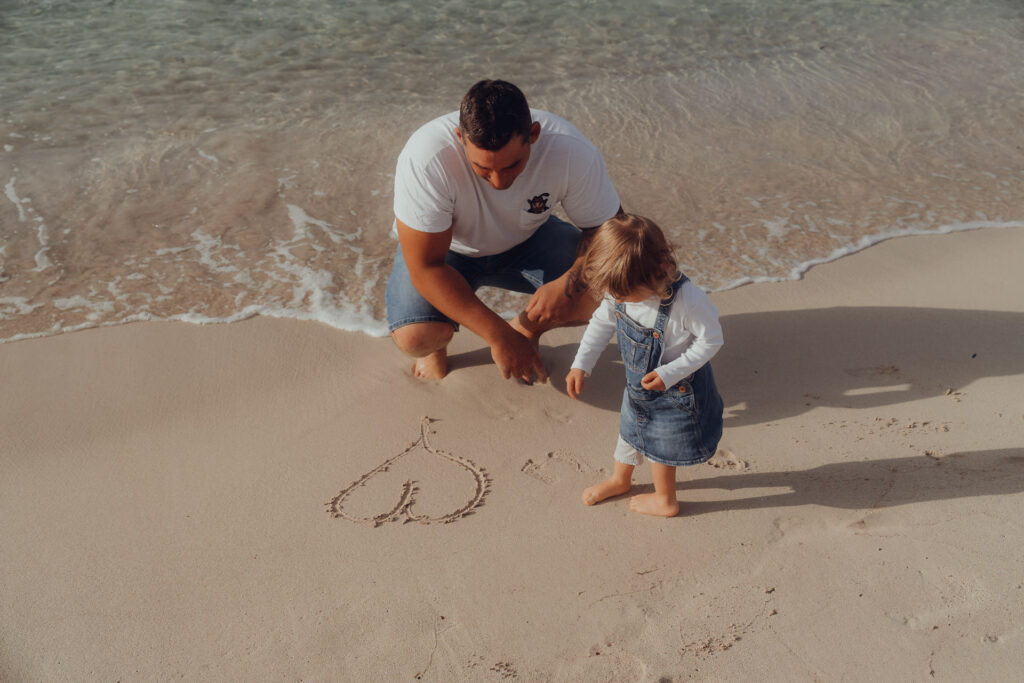 Vater und Kind malen Herz im Sand am Strand von Playa de Muro – emotionale Familienfotos beim Fotoshooting
