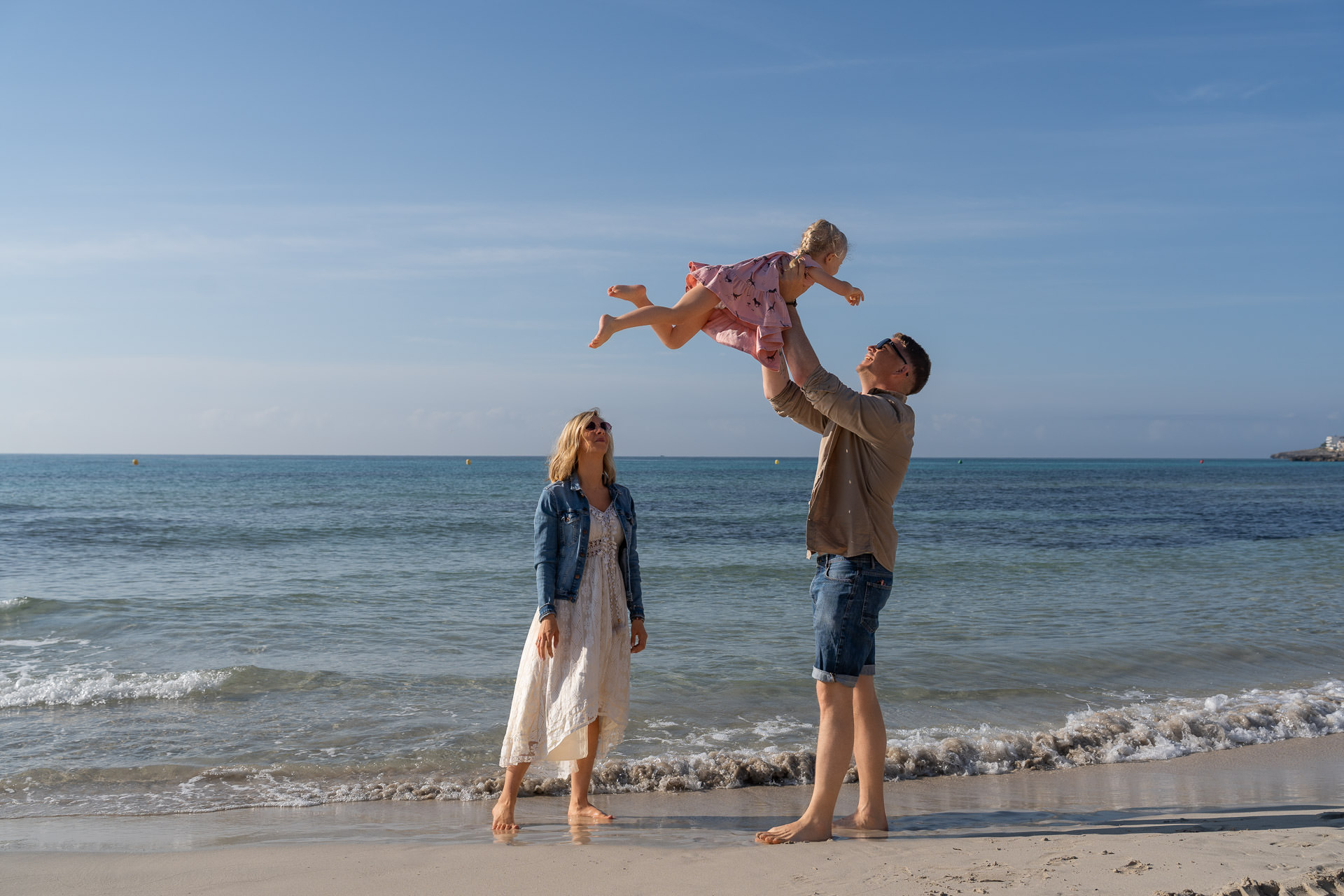Papa hebt lachendes Kind in die Luft – lockeres Sa Coma Fotoshooting am Strand