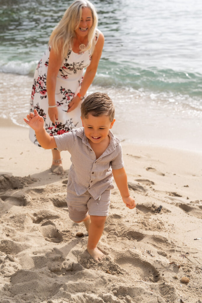 Kleinkind spielt fröhlich mit Mama und Papa im Sand – Sa Coma Fotoshooting